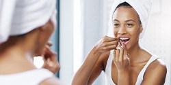 Closeup of woman flossing her teeth in bathroom