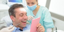 a patient checking his new dental bridge with a mirror