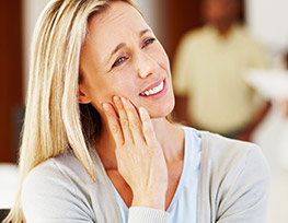 Blonde woman holding her cheek in pain