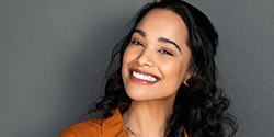 a woman smiling after repairing teeth with same-day dental crowns