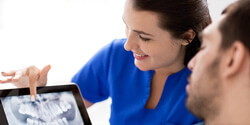 smiling dentist showing patient x-rays
