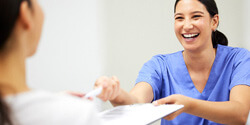 dental assistant smiling while handing patient form