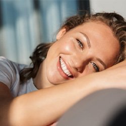 a woman smiling after getting new dental crowns