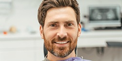 A smiling and bearded man sitting in a dental chair