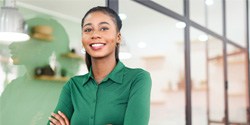 smiling person standing in an office with their arms crossed