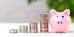 Coins next to piggy bank for cost of dental implants in Edmond