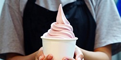 A person holding a cup of ice cream between their hands