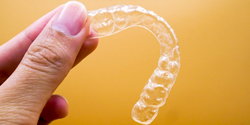 Hand holding an Invisalign aligner tray