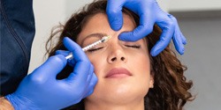 Woman receiving neurotoxin injection between her eyebrows