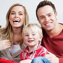 family of three showing off dazzling smiles after preventive dentistry