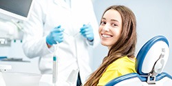 Woman in yellow shirt smiling in dentist's treatment chair