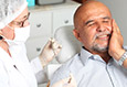 man holding cheek in severe pain before emergency dentistry