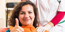 Woman in dental chair giving thumbs up