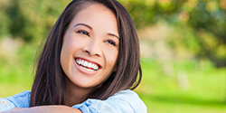 woman smiling vibrantly outside after metal free dental restorations