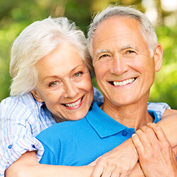 Older couple smiling after restorative dentistry