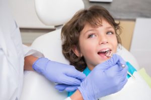 little boy smiling sitting dental chair