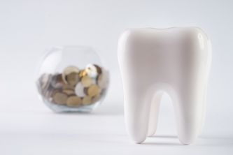 Model of a tooth next to a piggy bank