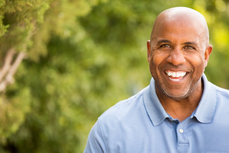 older man smiling after having teeth replaced with dental implants