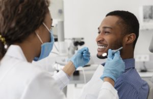 young man sitting in dental chair and smiling at his dentist 