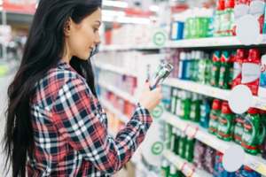 Woman wearing a plaid shirt standing in the dental care aisle of a store holding toothbrushes