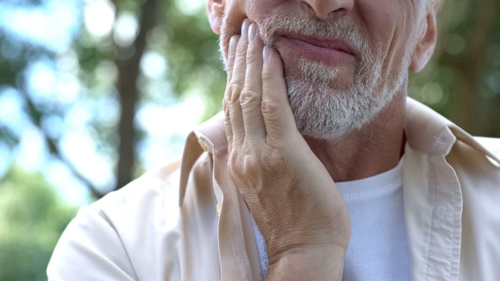 person with jaw pain holding their cheek