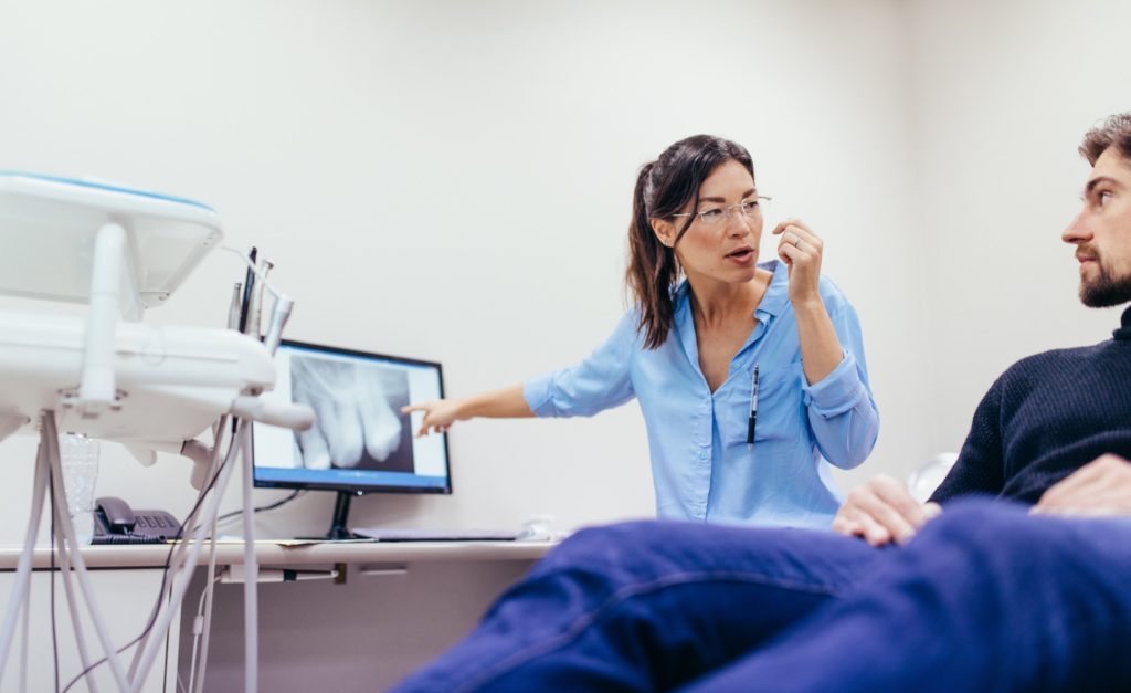 Female dentist pointing to X-ray and explaining it to patient