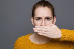 Woman with bad breath covering her mouth