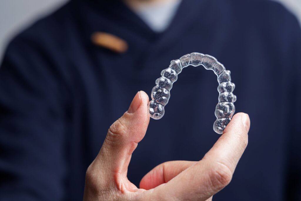 Man in navy scrubs holding Invisalign