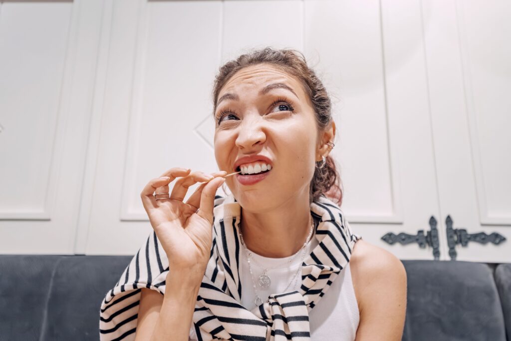 Woman with curly hair using toothpick to clean her teeth