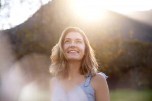 woman smiling in the sun outside being healthy