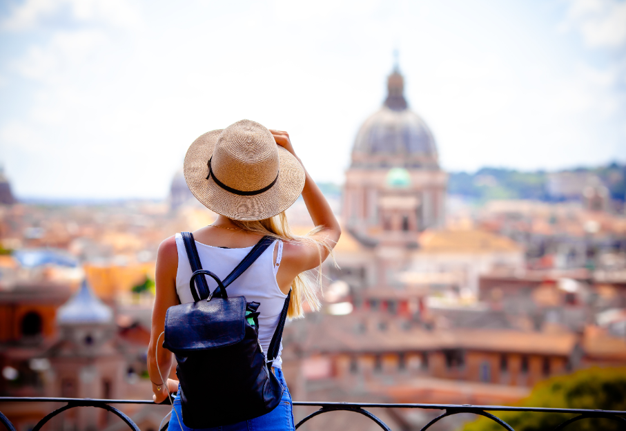 Woman with hat and backpack overlooking European city