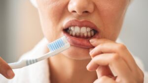 Person holding toothbrush showing bloody gums.